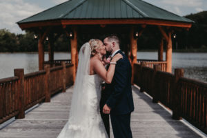 Young bride and groom share their first kiss as a married couple on a beautiful dock.