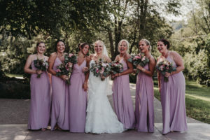A beautiful bride, standing center in between her bridesmaids, all sharing a laugh!
