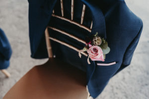 Groom's jacket over top of a golden chair, displaying a gorgeous boutonniere.