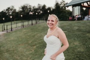 A candid shot of the bride as she holds up her dress to run down a grassy hill.